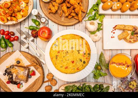 Recipes of typical Spanish dishes and tapas with potato omelette with vegetables, fried padrón peppers, Cordovan salmorejo, Madirleñas bravas potatoes Stock Photo