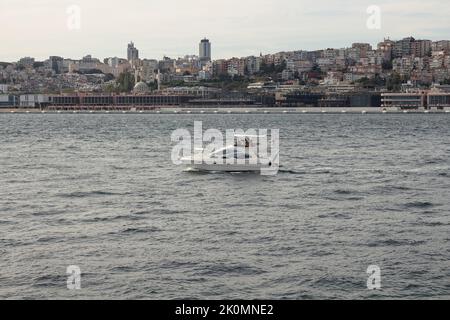 View of a yacht on Bosphorus and Beyoglu district on European side of Istanbul is in the background. It is a sunny summer day. Beautiful scene. Stock Photo