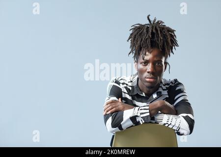 Portrait of African guy with stylish hairstyle looking at camera isolated on blue background Stock Photo