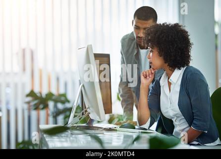 Two designers are better than one. designers talking together at a workstation in an office. Stock Photo