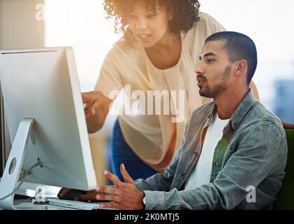 Tweaking their project. designers talking together at a workstation in an office. Stock Photo