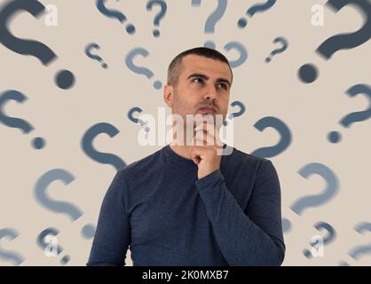 Close up photo of pensive and thoughtful man with the question marks on the backround. Concept of FAQ and mindblowing to find answer to questions. Stock Photo
