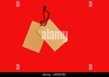 Empty brown cardboard tag with string on red background. Vintage paper textured tag. Mockup cardboard label. Price tag, gift tag, sale tag, address la Stock Photo