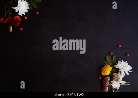 Atmospheric autumn background with flowers: marigold, chrysanthemum and rowan berries on black background. Copy space. Stock Photo