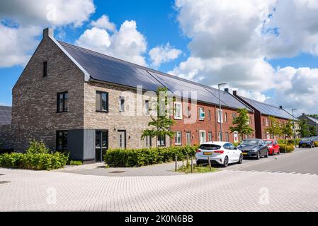 Row of new energy efficient brick terraced houses with the toproof covered with solar panels on a sunny day Stock Photo