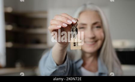 Old happy woman homeowner buyer female mature lady seller realtor tenant adult caucasian granny show bunch keys of accommodation house rental flat win Stock Photo