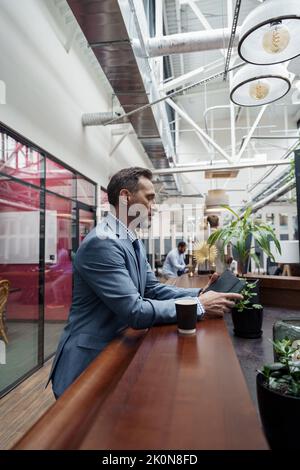 Handsome businessman standing in office during break and use phone Stock Photo