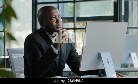 Thoughtful dreamy african man executive worker teacher male team leader has dilemma question thinking decision brainstorming create startup project Stock Photo