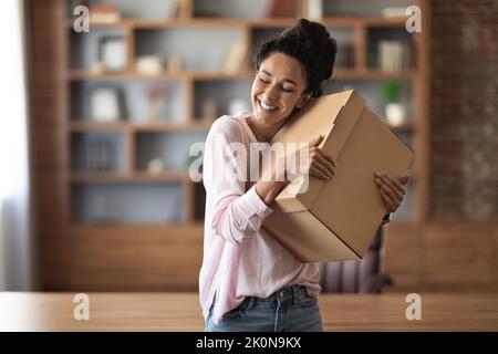 Happy young lady embracing box with something inside Stock Photo
