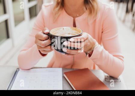 Faceless close up of woman holding cup of coffee outside coffee shop Stock Photo