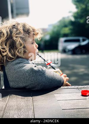 child drinking water from a straw Stock Photo