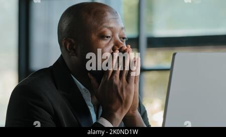 Tired stressful african male adult sad businessman feel tiredness discomfort eyestrain fatigue pain from hard overwhelmed computer work massaging dry Stock Photo