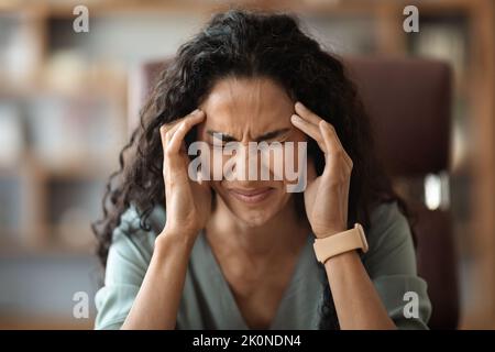 Unhappy young lady suffering from migraine while working Stock Photo
