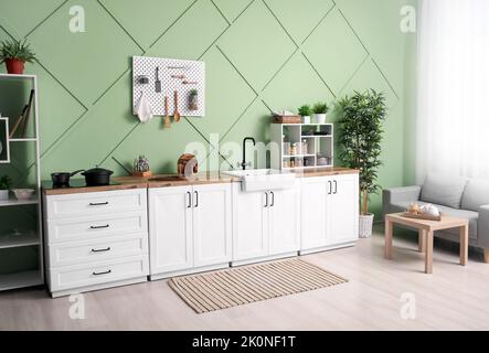 Interior of stylish kitchen with white counters, pegboard and shelving units Stock Photo