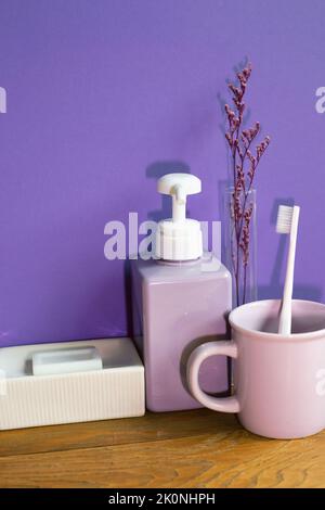 Bathroom accessories hygiene objects on wooden table. purple wall background Stock Photo