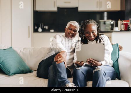 Mature couple smiling happily while having a video call on a digital tablet. Cheerful senior couple communicating with their loved ones online. Mature Stock Photo