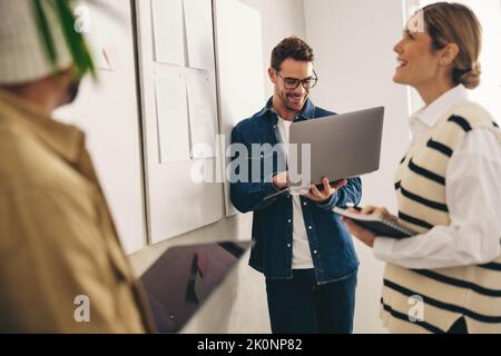 Happy businesspeople analysing some reports on a notice board during a meeting in a creative office. Group of diverse businesspeople working as a team Stock Photo