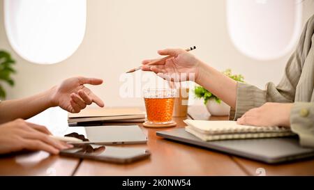 Two talented Asian female college students discussing and planning their project assignment details in the cafe co-working space. cropped image Stock Photo