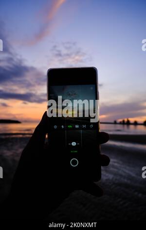 Woman holding mobile phone in hands and taking sunrise photo Stock Photo