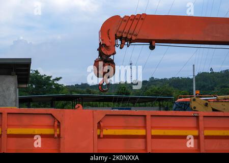 Red lifting crane hook with tower on mobile crane in construction site. Stock Photo