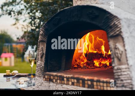 Wood-fired pizza oven with birch logs for kindling. The fire burns and the  oven heats up. Front view Stock Photo - Alamy