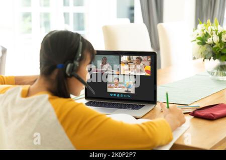 Asian girl using laptop for video call, with smiling diverse elementary school pupils on screen. communication technology and online education, digita Stock Photo