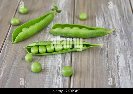 Opened pods of fresh green peas on wooden background Stock Photo