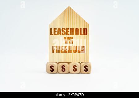 Real estate and business. On a white surface stands a wooden model of a house with the inscription - Leasehold vs Freehold Stock Photo