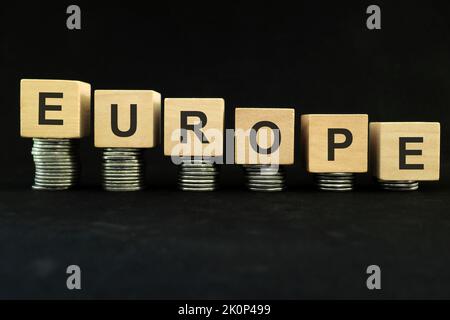 European economic recession, crash, collapse, crisis and Europe economy down concept. Wooden blocks in with coins in dark black background. Stock Photo