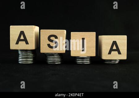 Asian economic recession, crash, collapse, crisis and Asia economy down concept. Wooden blocks in with coins in dark black background. Stock Photo
