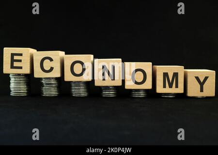 Economic recession, crash, collapse, crisis and economy down concept. Wooden blocks in with coins in dark black background. Stock Photo