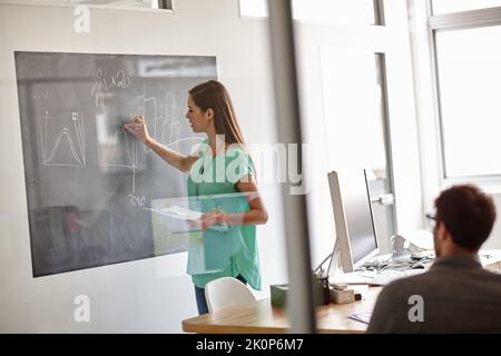 I have done the work to achieve my goals. a young designer describing her statistical analysis on a blackboard. Stock Photo