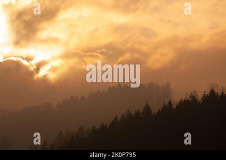 The brightness of the sun forms very different clouds and makes the mountain very mysterious and misty. Stock Photo