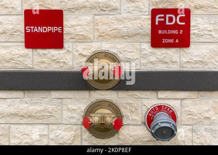 Manual standpipes, automatic sprinkler fire department connection, red signs with inscriptions on the wall of building Stock Photo