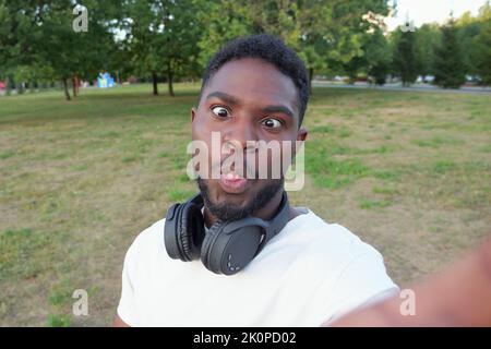 African American man makes selfies grimacing against park Stock Photo