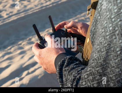 Male hands holding drone remote controller. Cropped shot, close up. Stock Photo