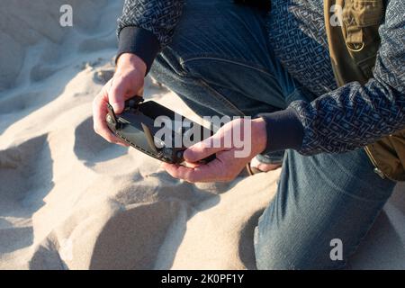 Male hands holding drone remote controller. Cropped shot, close up. Stock Photo