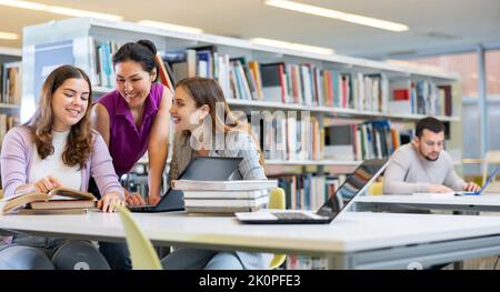 Three young women preparing for exams together in public library Stock Photo