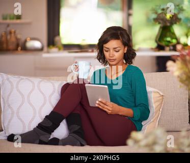 Wireless and worry free weekend. a young woman using a digital tablet on the sofa at home. Stock Photo