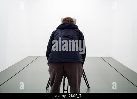 Woman with her back turned looks at the camera on a tripod in an art gallery. Conceptual photo Stock Photo