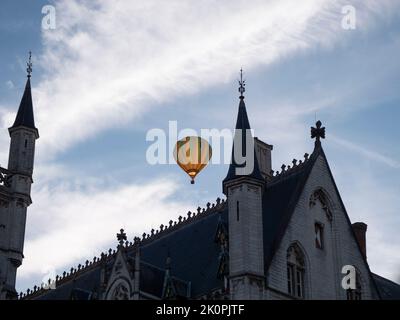 Colorful hot air balloon flies over the neo-gothic town hall of the city of Sint Niklaas in Belgium Stock Photo