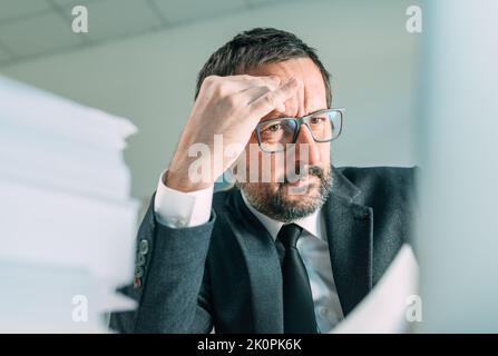 Serious business situation causing headache in office life, worried businessman looking at laptop screen and thinking, selective focus Stock Photo