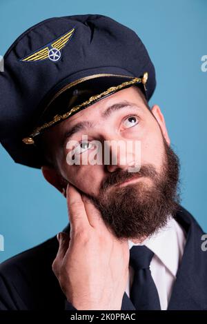 Pensive confused airline pilot in uniform questioning, making decision ...