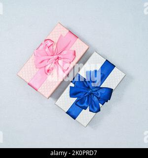 Two gifts with blue and pink ribbons on silver background. FLat lay Stock Photo
