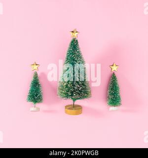 Three Christmas trees on pastel pink background. Flat lay Stock Photo