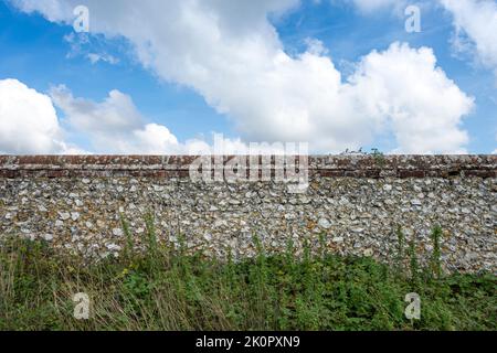 old flint and stone wall with sky background. Stock Photo