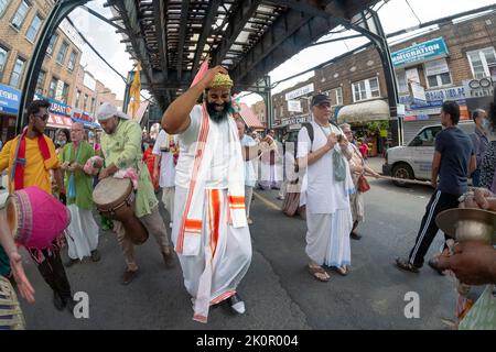 Ecstatic Hare Krishna Hindus dance & play music under the elevated subway at the annual Ratha Yatra parade in Richmond Hill, Queens, New York. Stock Photo