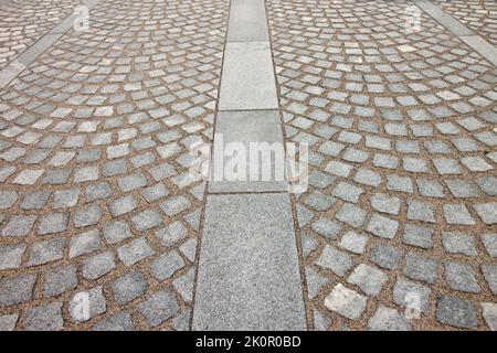 New paving made with grey stone slabs and small stone cube blocks interlocked with sand in curved shape in a pedestrian zone Stock Photo