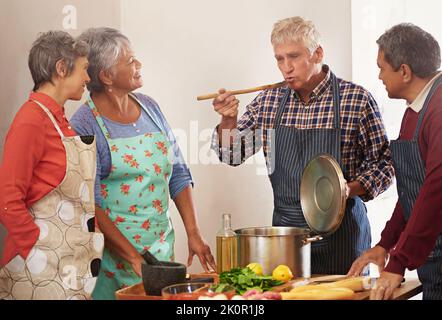 People who love to eat are always the best people. a group of seniors cooking in the kitchen. Stock Photo