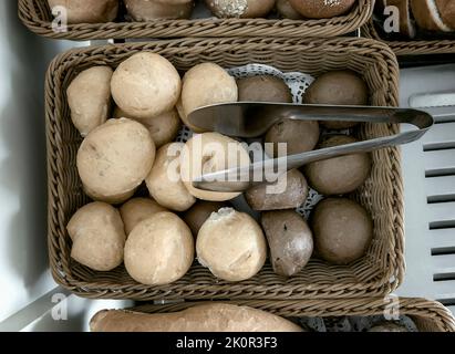 Delicious buns are on the table in a wicker basket. Top view, close-up. Stock Photo